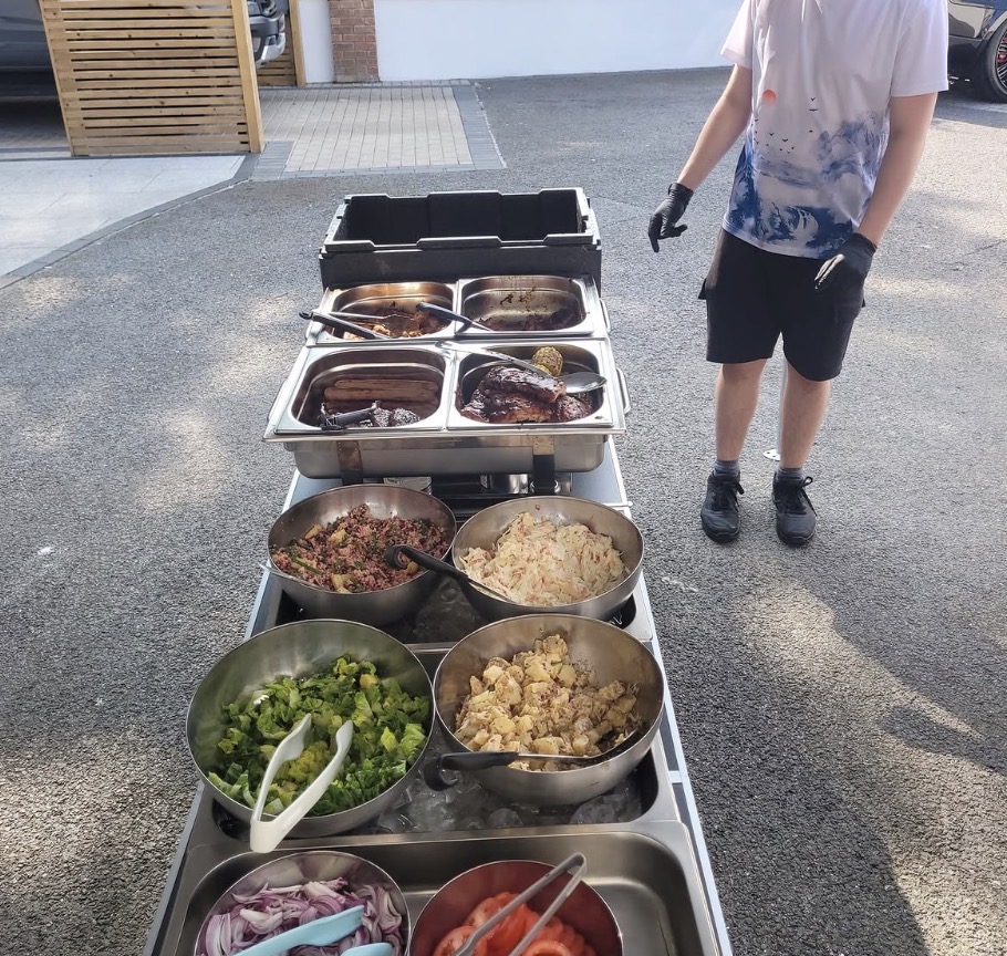 Buffet line with chafing dishes of BBQ meats and fresh salads
